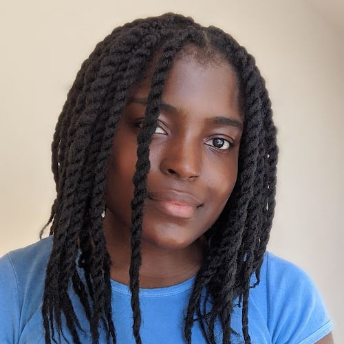 A photo of Yasmine Simone Gray. Yasmine has dark skin and long black hair worn in twists. She is wearing a blue T-shirt.